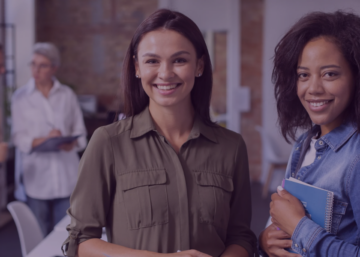 Duas mulheres sorrindo em um ambiente de trabalho, representando áreas de Recursos Humanos e Departamento Pessoal.