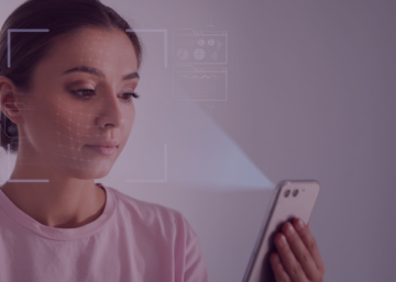 Mulher usando reconhecimento facial no celular para registrar ponto eletrônico em ambiente de trabalho.