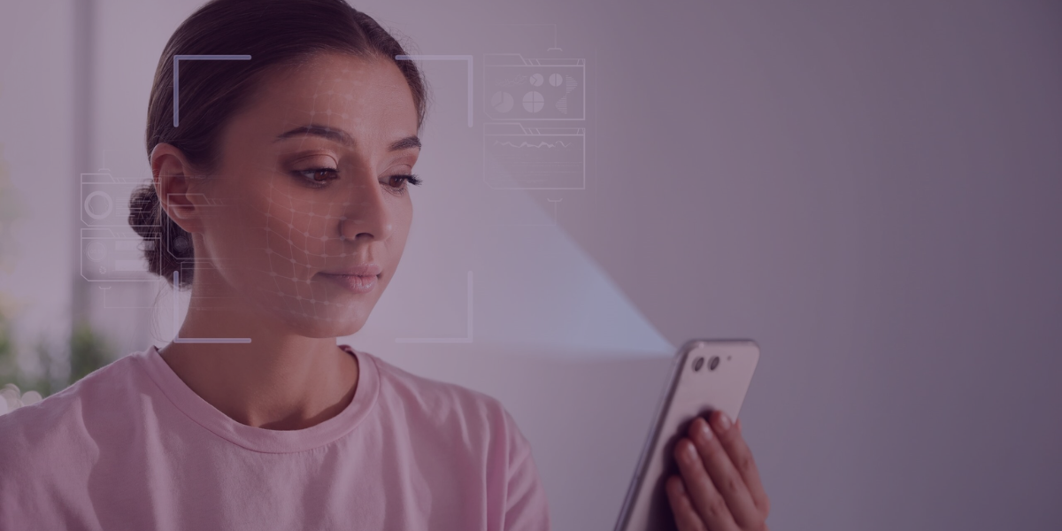 Mulher usando reconhecimento facial no celular para registrar ponto eletrônico em ambiente de trabalho.